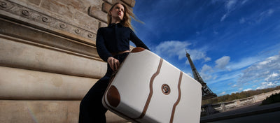 Woman in front of the Eifel tower holding the Chatelet Large Suitcase in the color angora with brown trim.