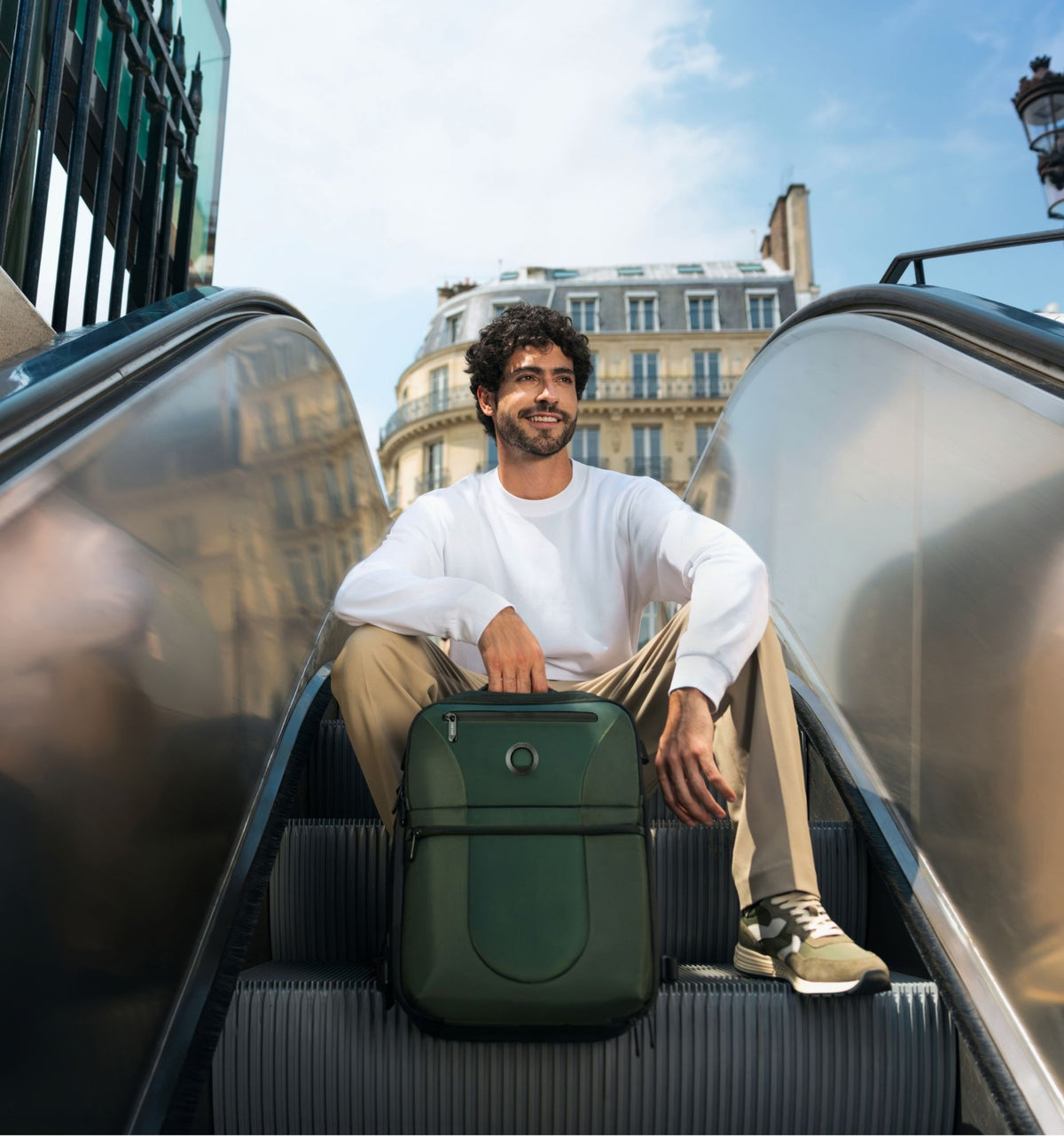 Traveler riding an escalator with a compact green Delsey bag at his feet